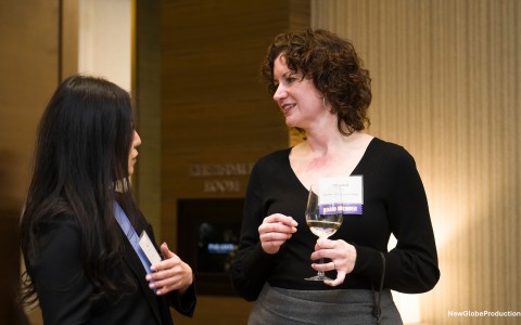 a woman holding a wine glass and talking to another woman