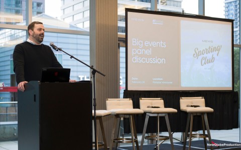 a man standing at a podium with a screen and chairs