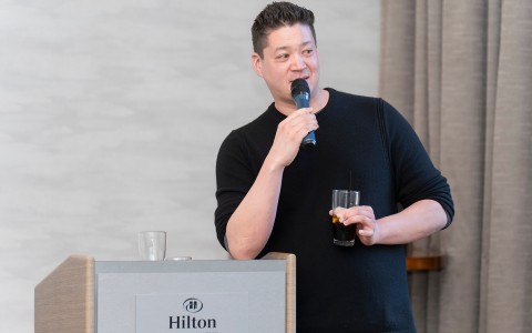a man holding a microphone and a drink