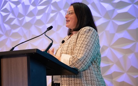 a woman standing at a podium with microphones