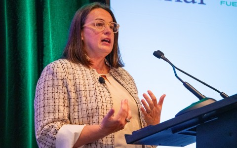 a woman standing at a podium with her hands in front of her
