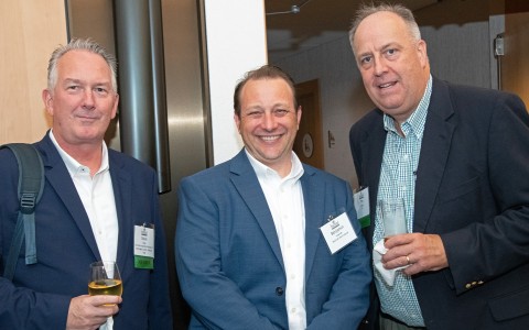 a group of men smiling and holding drinks