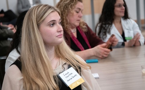 a woman sitting at a table with a name tag