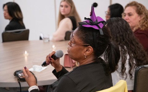 a woman wearing a purple hat and holding a microphone