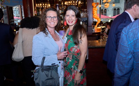 two women standing together smiling at the camera