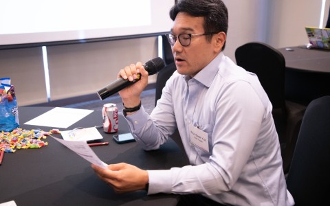 a man holding a microphone and looking at a paper