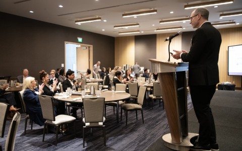a man standing at a podium with a microphone in front of a group of people