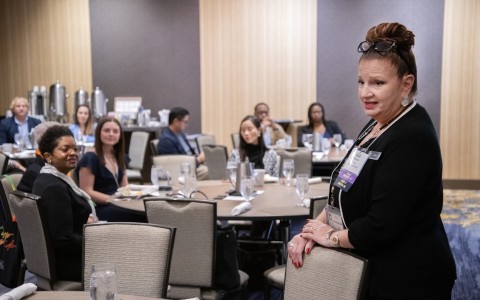a woman standing in a room with other people around
