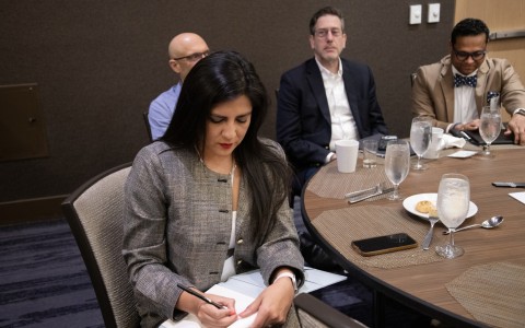 a woman sitting at a table writing on a notepad