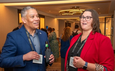 a man and woman standing in a room with a beer