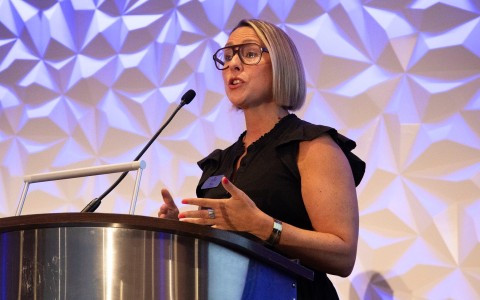 a woman standing at a podium speaking into a microphone