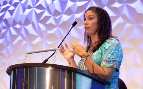 a woman standing at a podium with a microphone