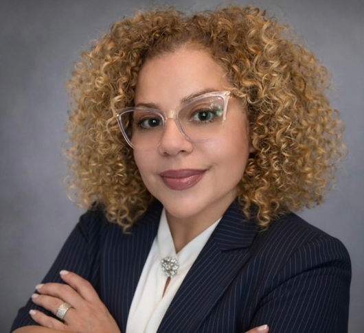 a woman with curly blonde hair wearing glasses and a suit