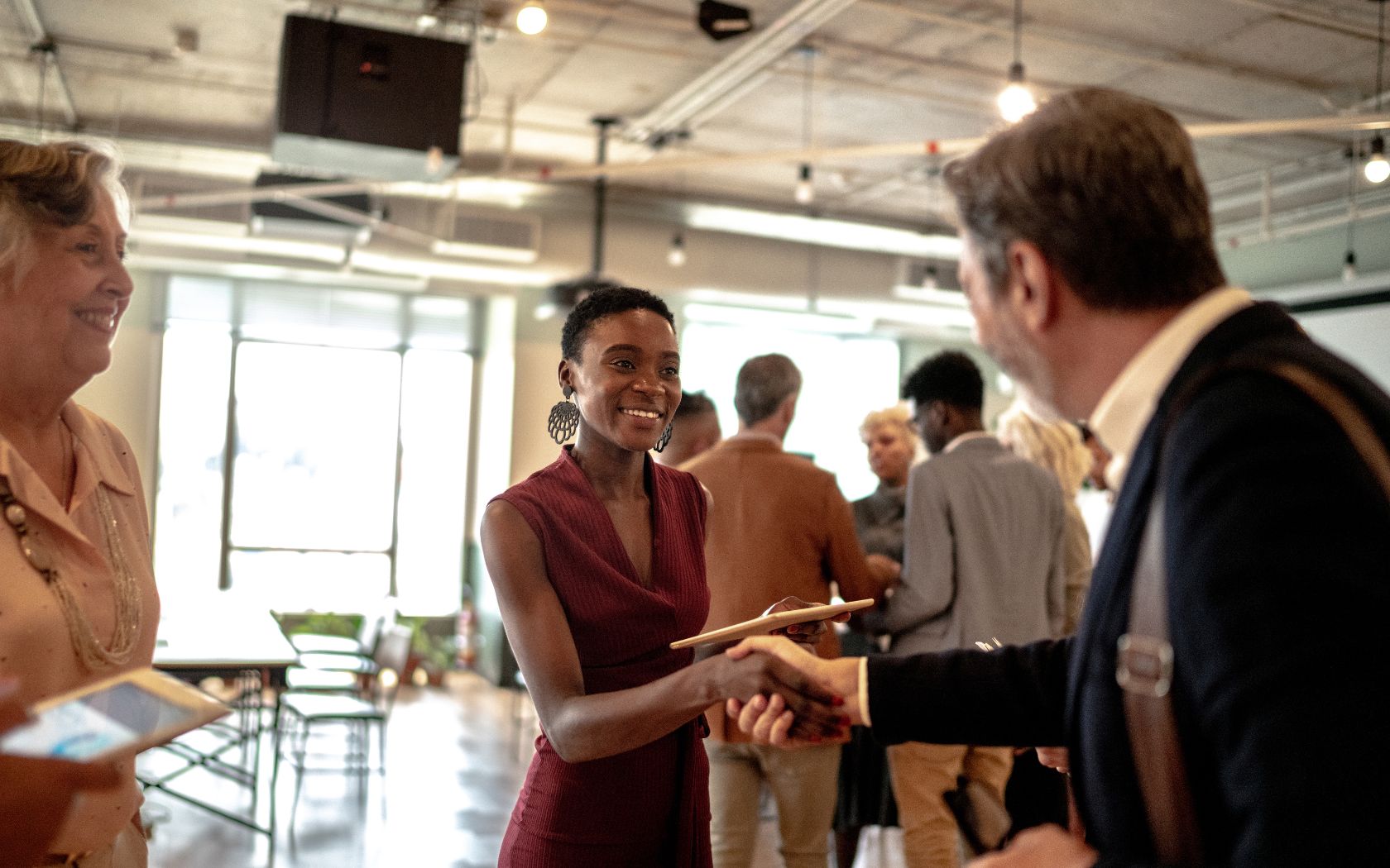 a woman shaking hands with a man in a room with other people