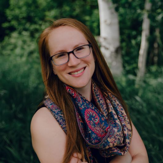 a woman smiling with glasses and a scarf