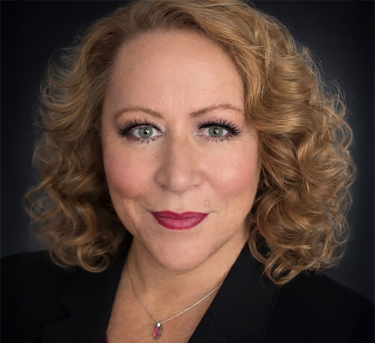 a woman with curly blonde hair wearing a black suit