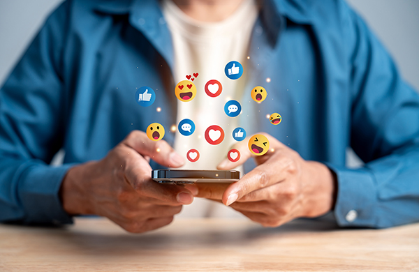 a person holding a phone with emojis flying out of it