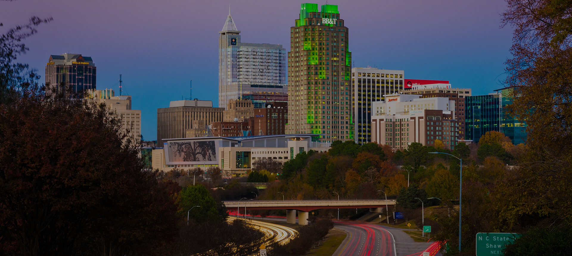 a city skyline with trees and a freeway