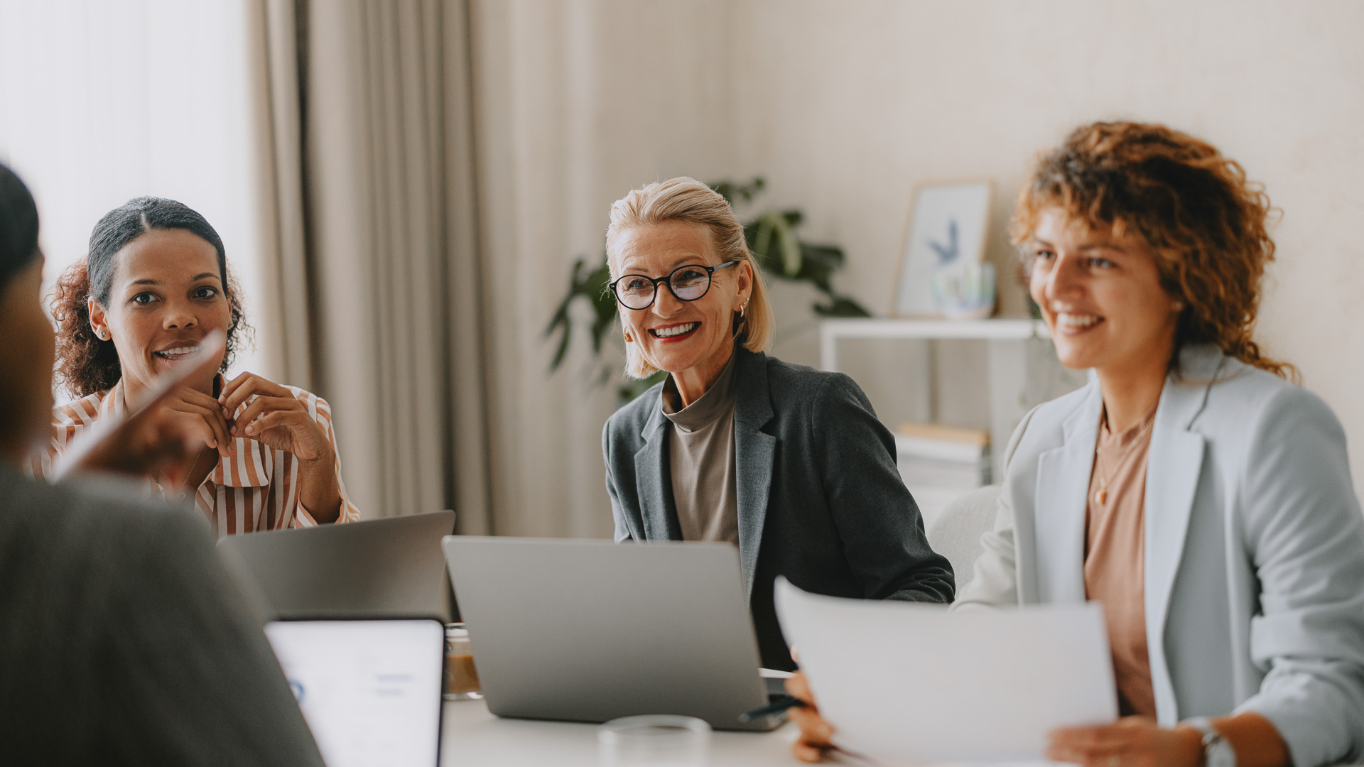 a group of people sitting at a table with laptops