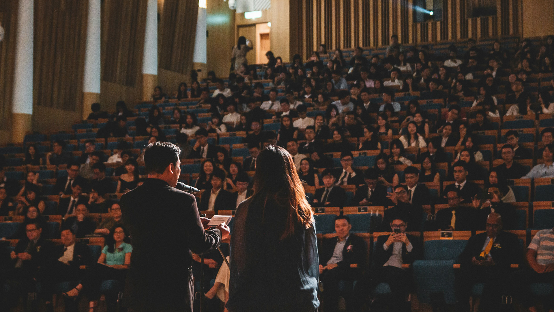 a man and woman standing in front of a large audience