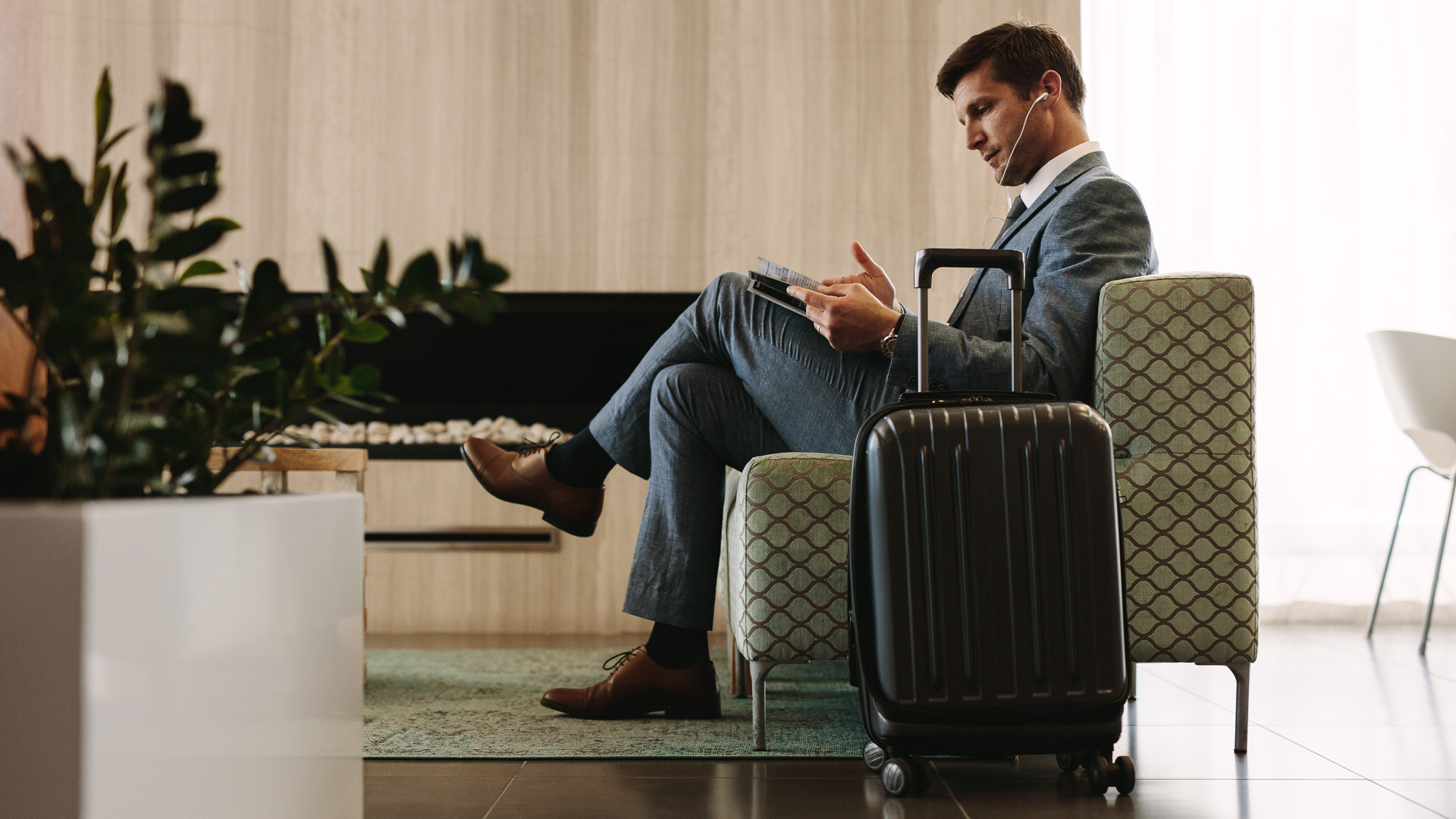 a man sitting in a chair with a suitcase and a tablet
