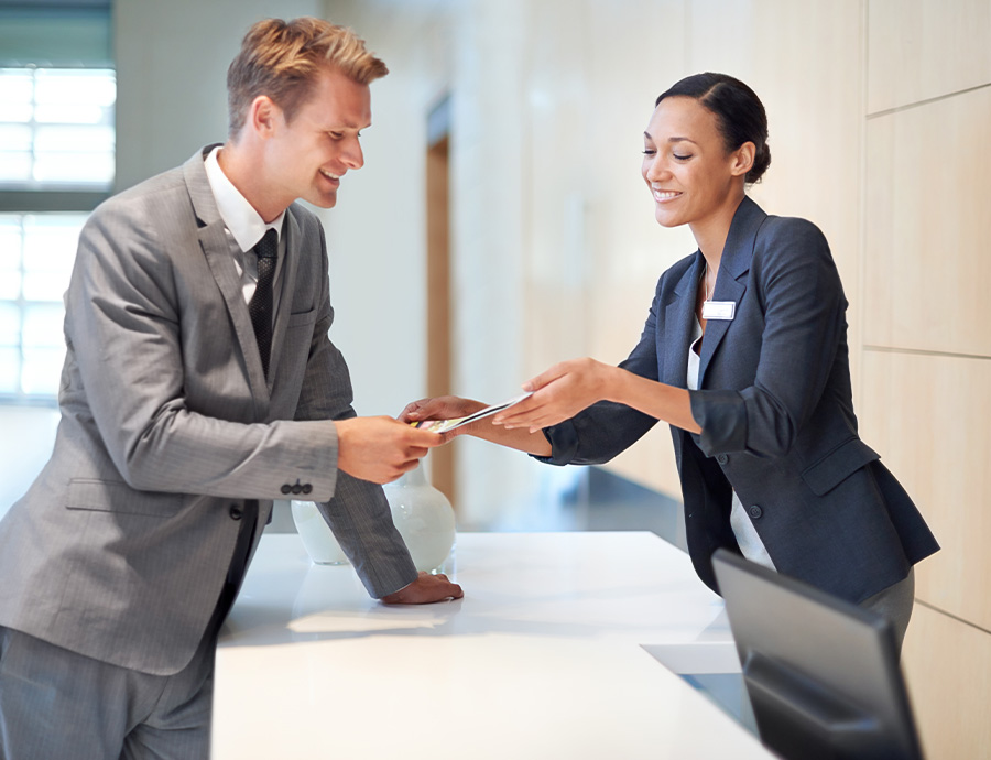 a man and woman in suits handing over a card to a woman