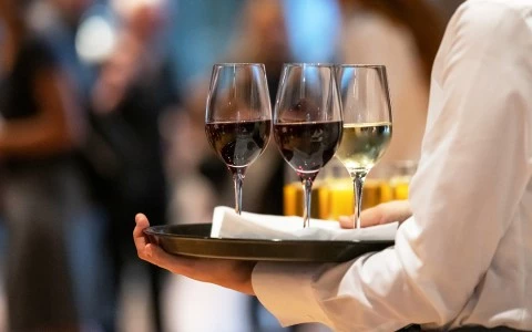 a person holding a plate with wine glasses on it