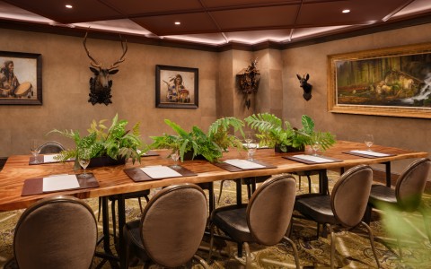 a room with a table with plants and a deer head mounted on the wall