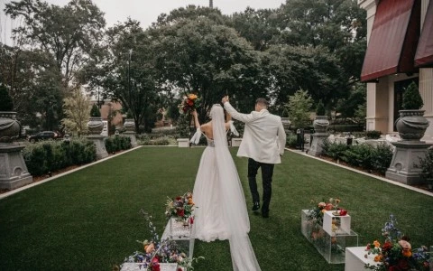 a man and woman walking down a path with flowers and trees