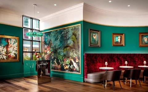 Green, floral interior with red velvet seating booths 