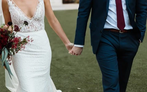 Close up of bride and groom holding hands 