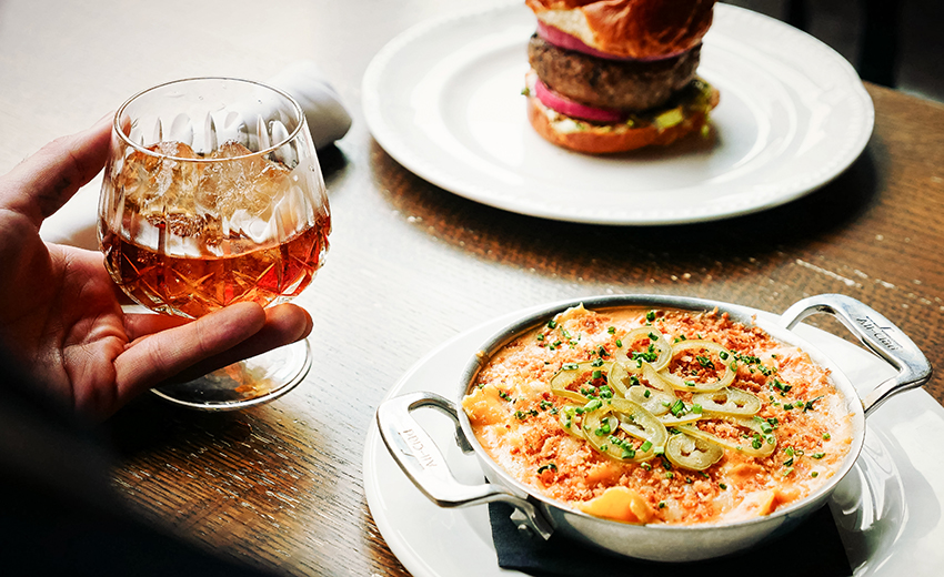 table with two delicious plates of food and a fancy whickey glass