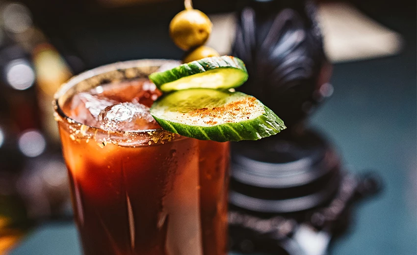 tall glasses filled with bloody marys and garnished with cucumber and olive