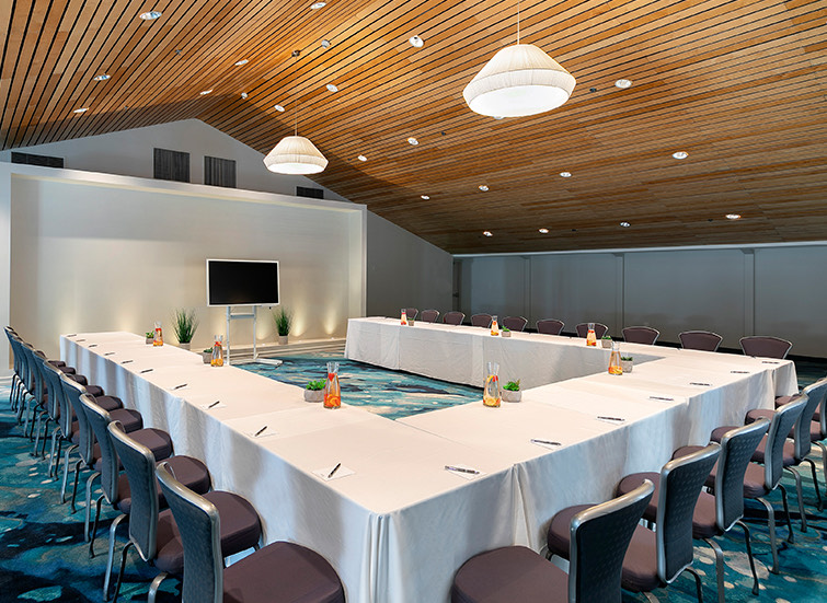 meeting space with tables in the shape of a U with white tablecloth