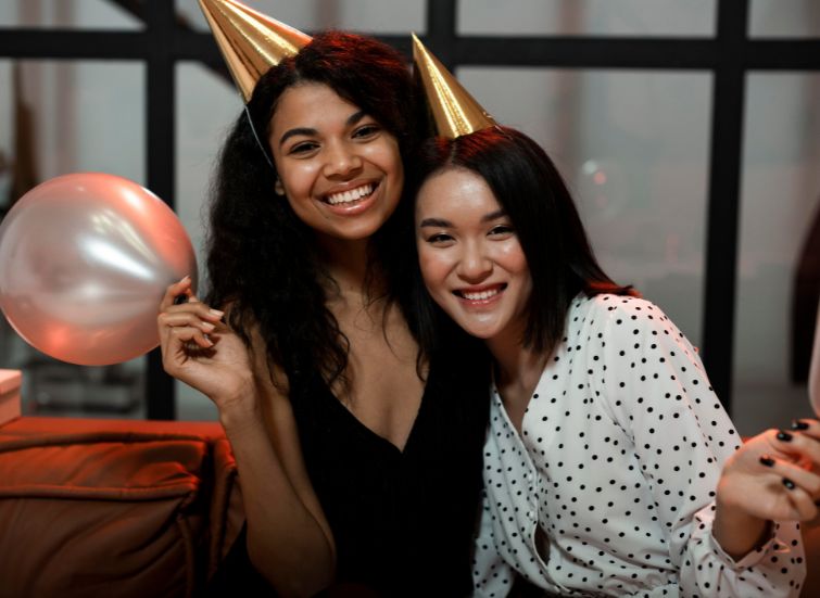 two women wearing party hats and smiling