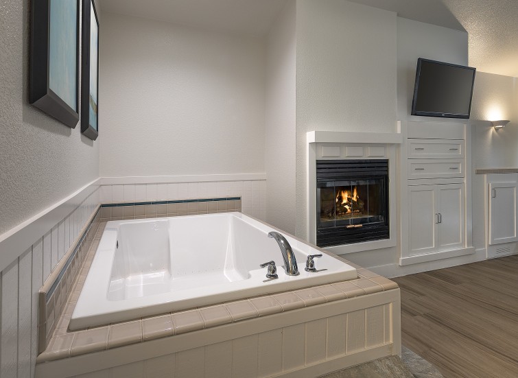 a white bathtub in a room with a fireplace