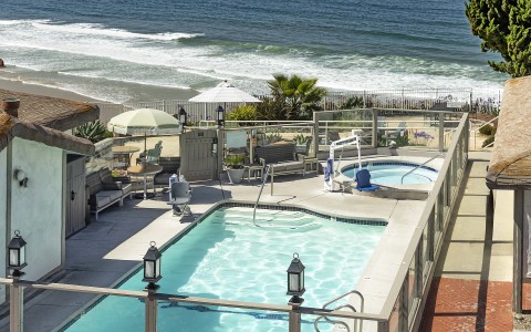 a swimming pool with a fence and a beach in the background