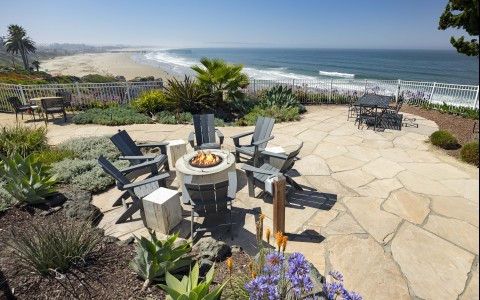 a patio with chairs and a fire pit on a beach