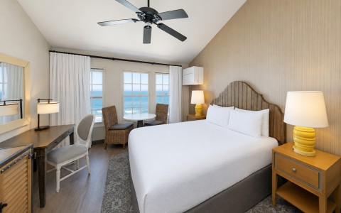 a room with a bed and a desk and a fan