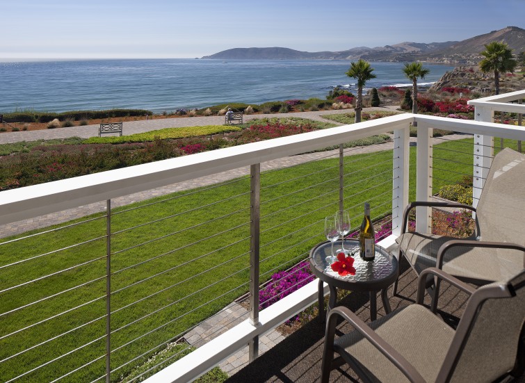 a table with wine and glasses on a balcony overlooking a body of water