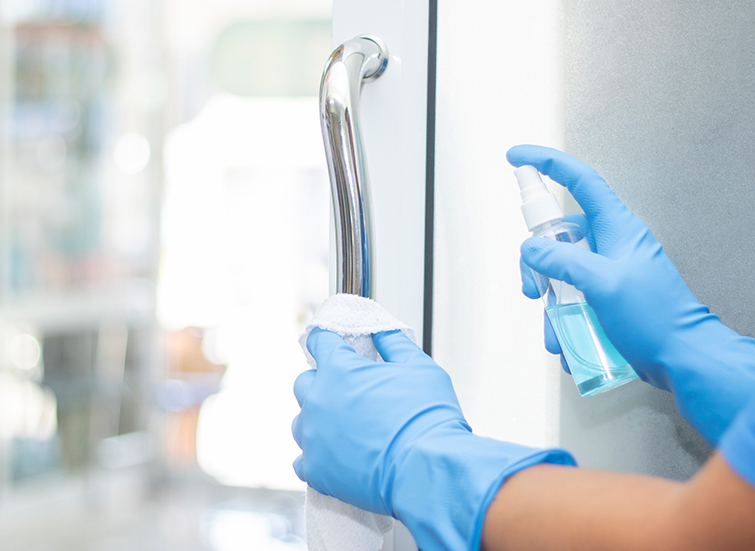 gloved hands wiping down a door handle