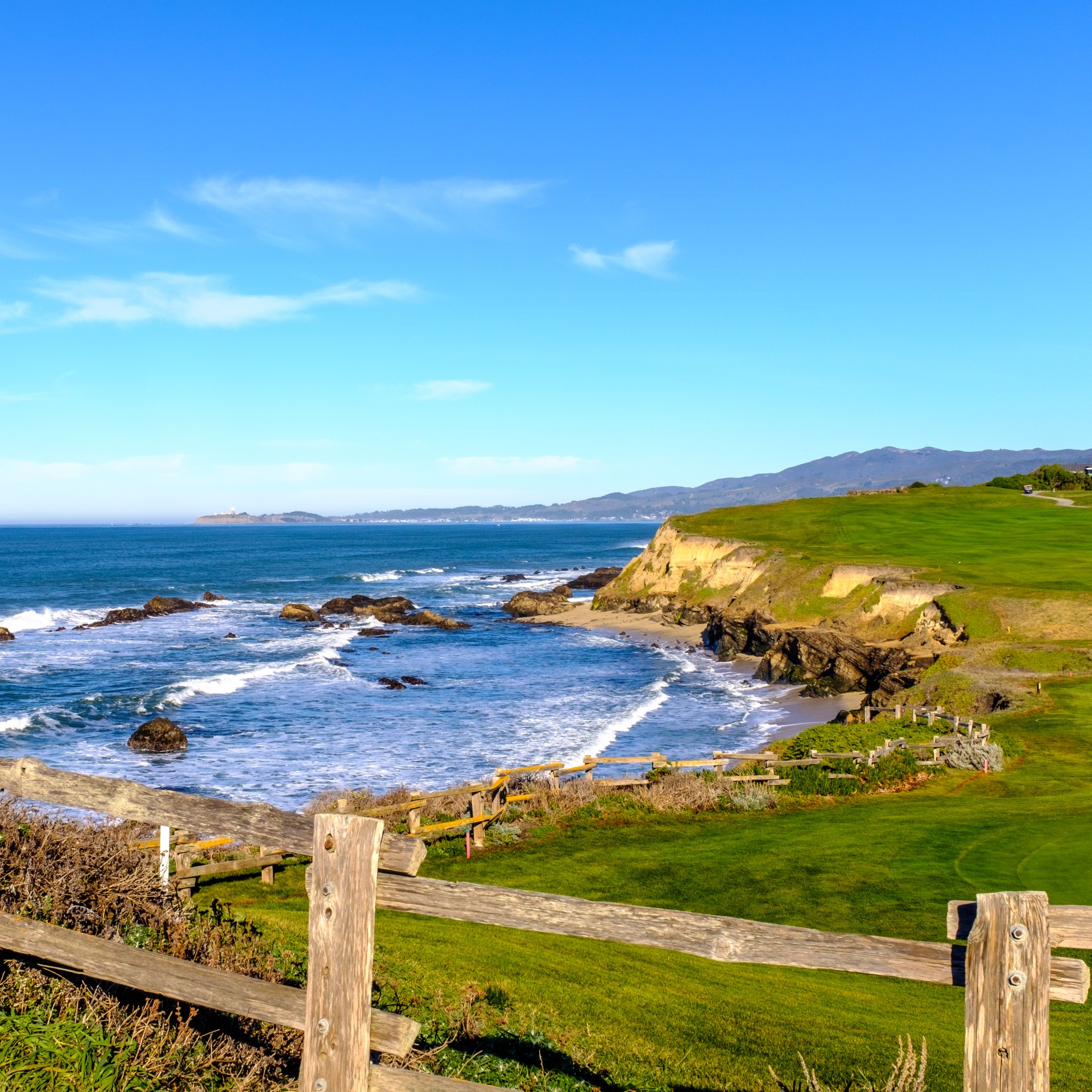 a fenced in beach with ocean and hills