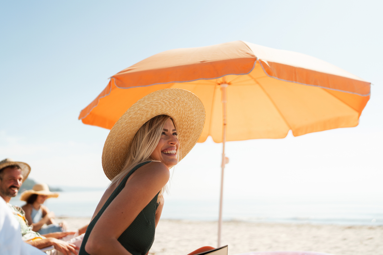 a woman wearing a hat and sitting on a beach
