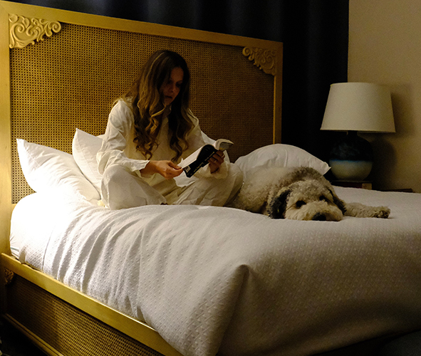 a woman sitting on a bed with a dog