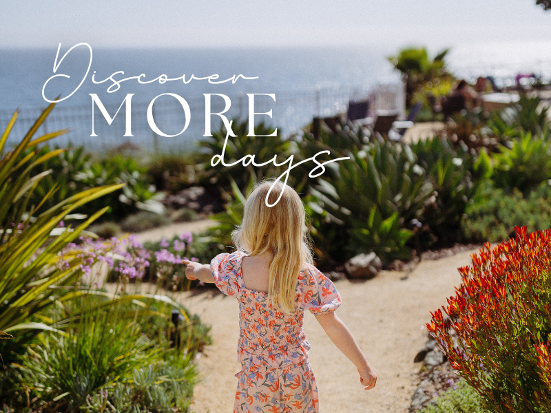 a girl walking on a path with plants and flowers