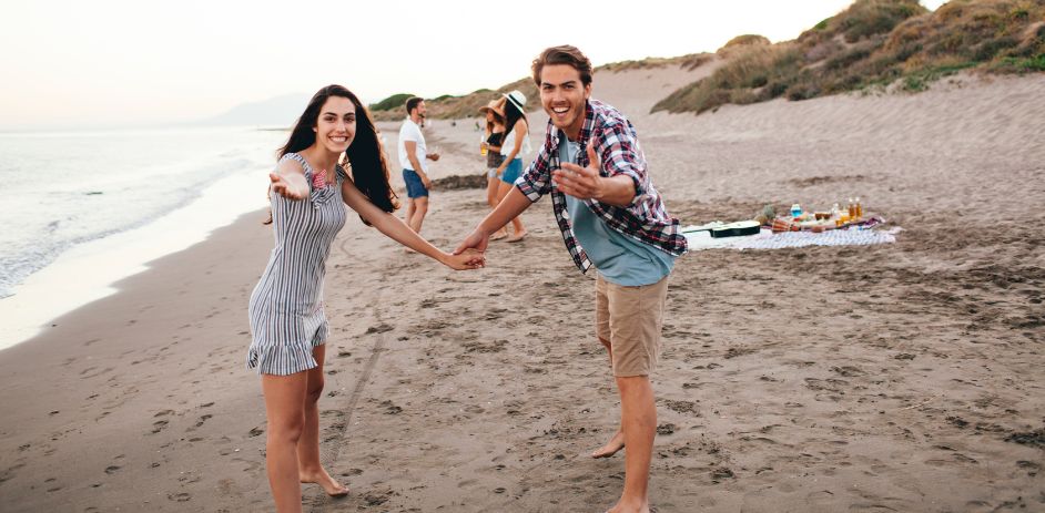 a man and woman holding hands on a beach