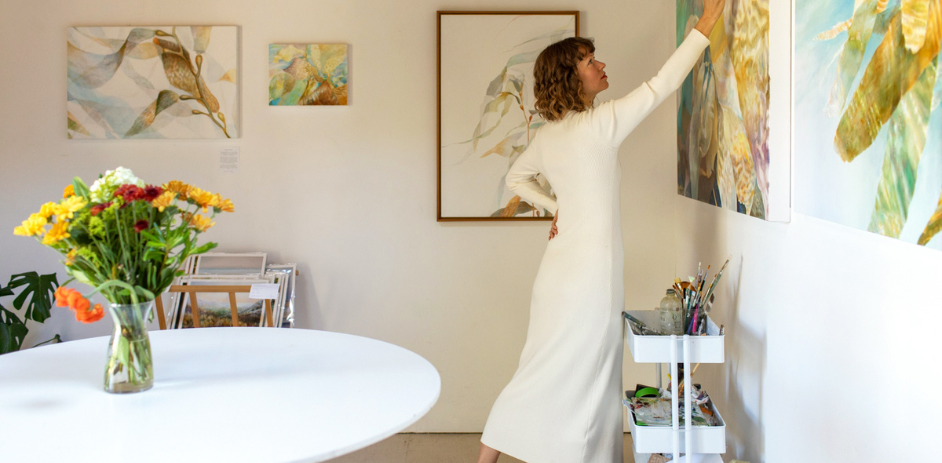 a woman in a white dress painting on a wall