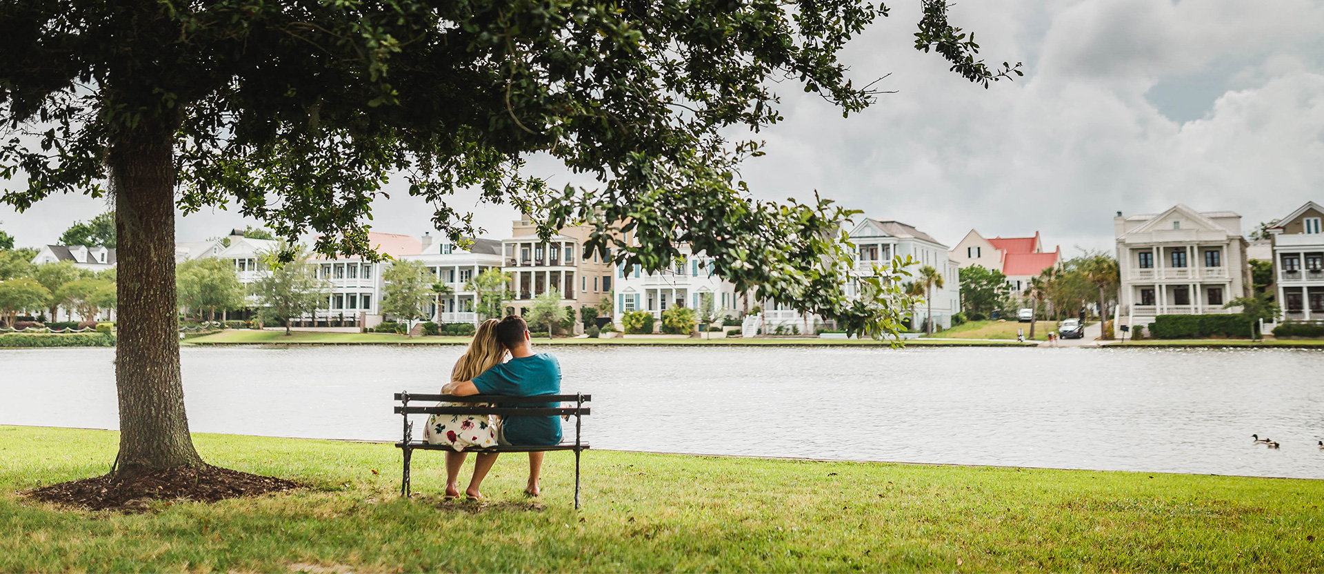 a couple sitting on a bench in front of a lake