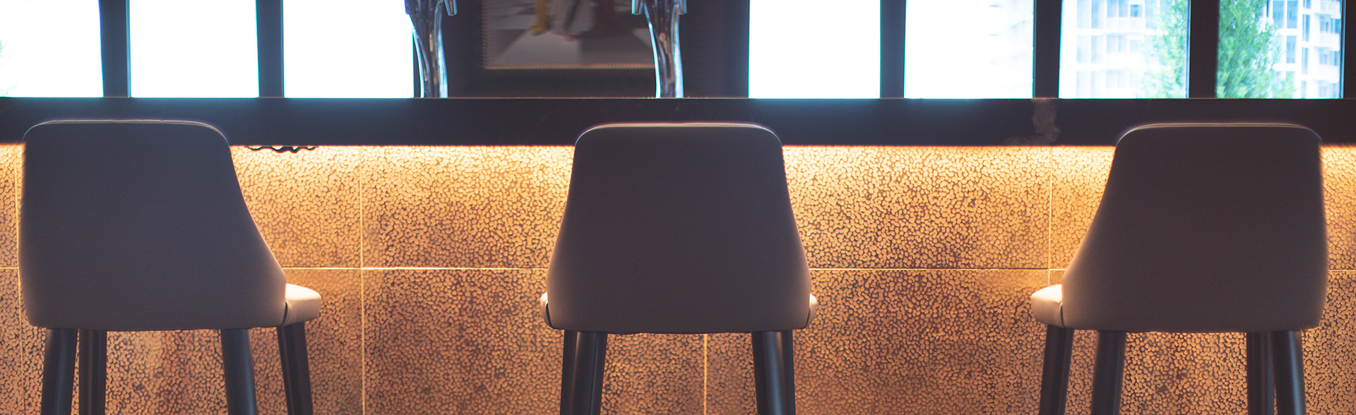 Three neutral colored bar stools pushed into bar.