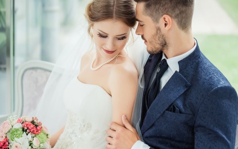 close up of a newly wedded couple standing close together as they take professional pictures